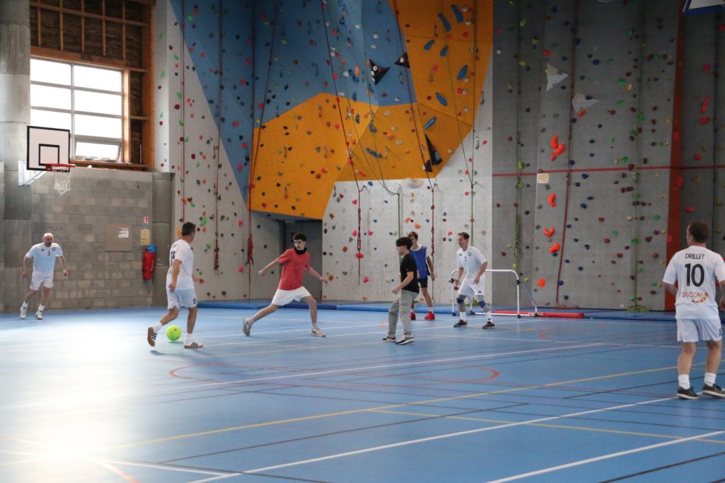 Elèves et professeurs qui jouent au foot dans le gymnase